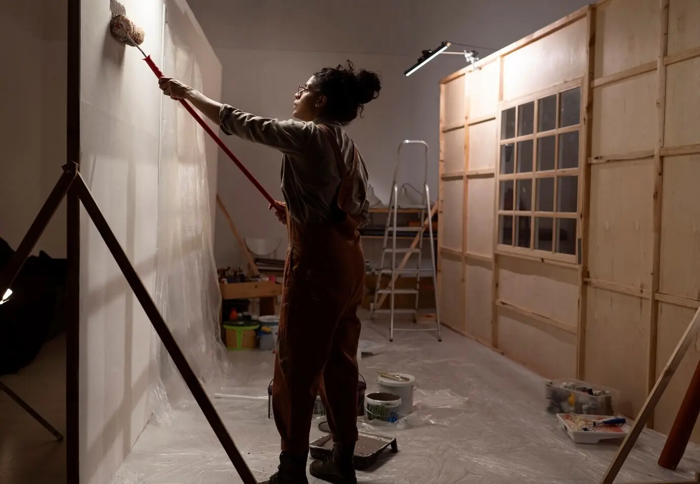 Full-length shot of a woman painting a wall.