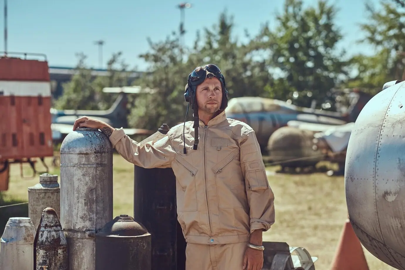 A portrait of a pilot in uniform and a flight helmet near combat bombs for a bomber aircraft at an open-air museum.